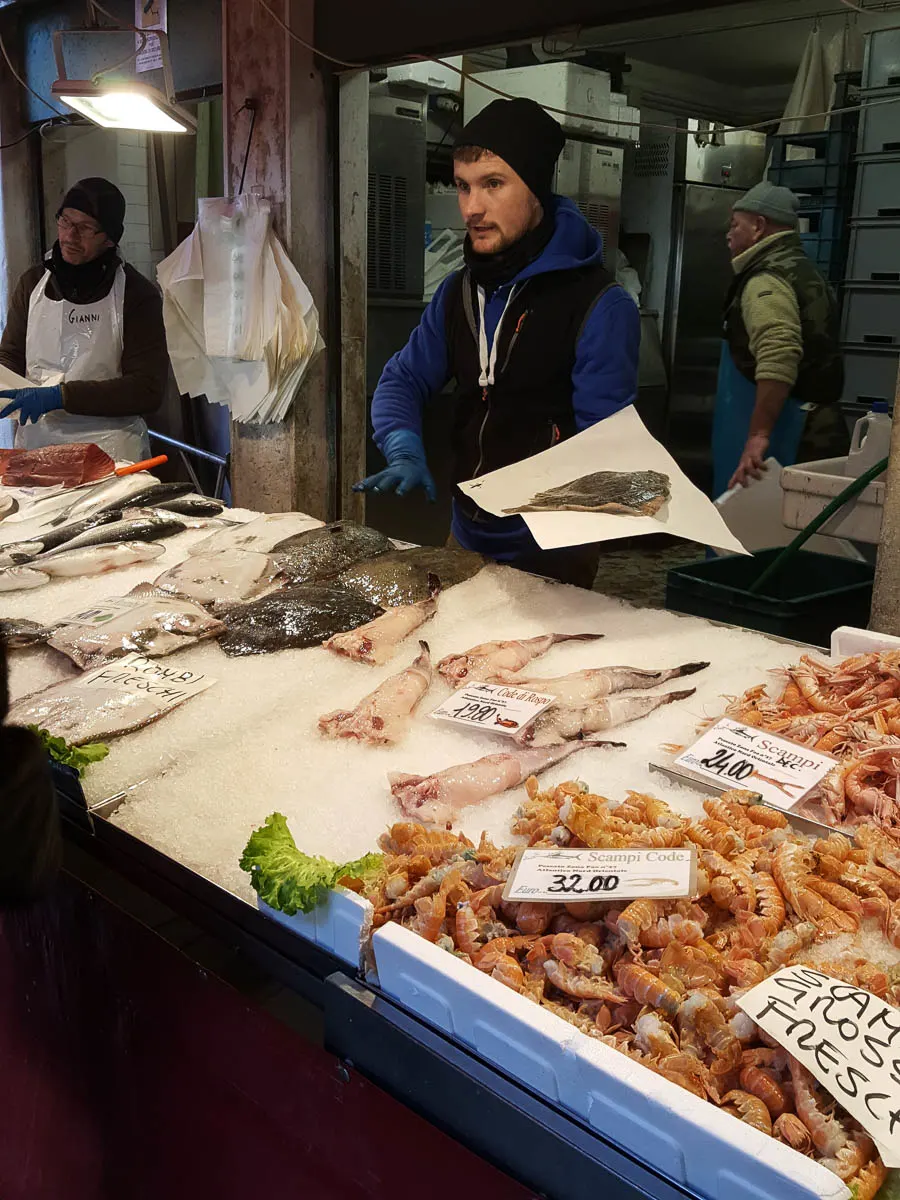 A fishmonger selling fish - Rialto Fish Market, Venice, Italy - www.rossiwrites.com