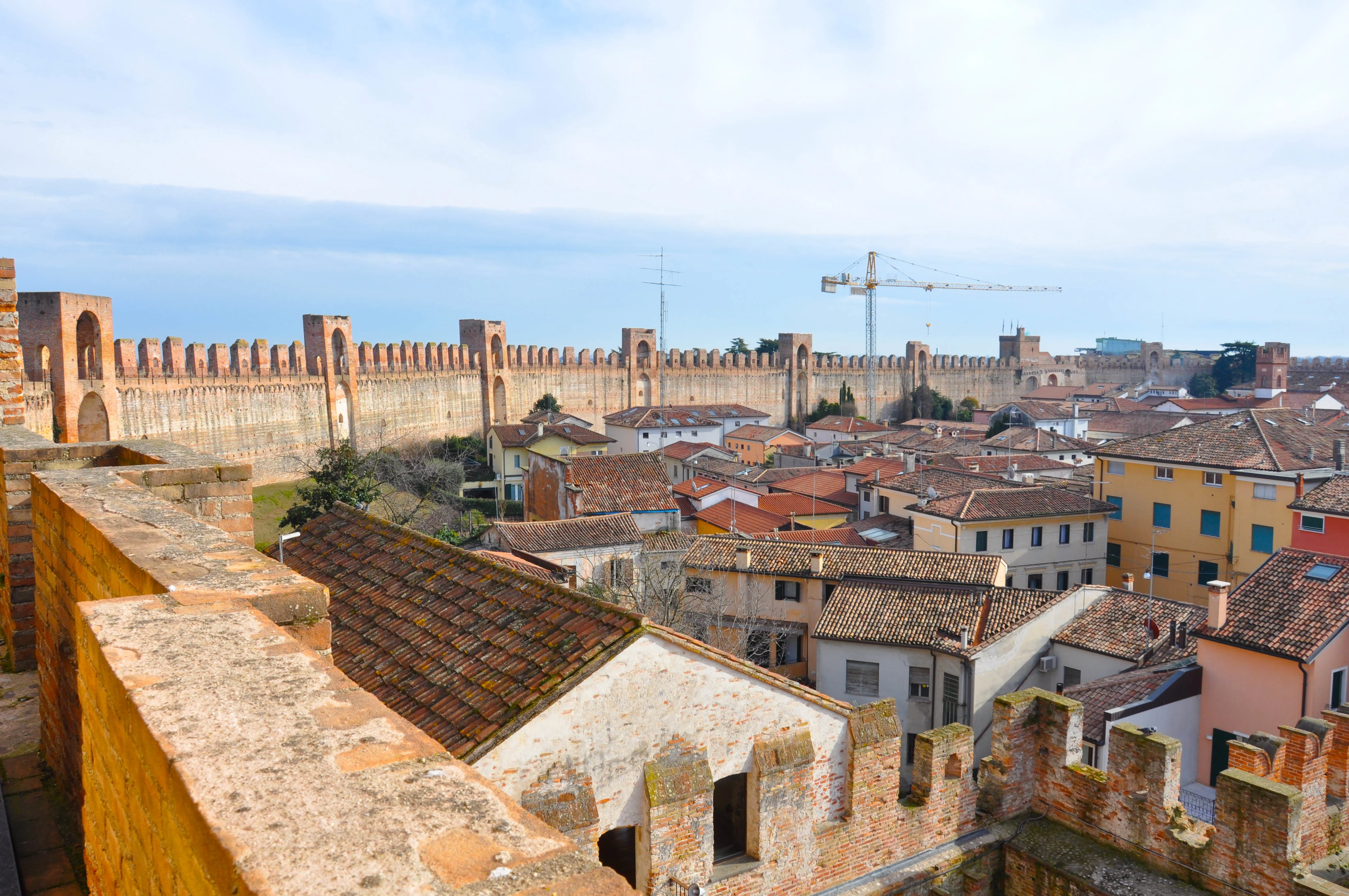 The medieval wall of the town of Cittadella in Italy with a crane in the distance - Veneto, Italy - www.rossiwrites.com