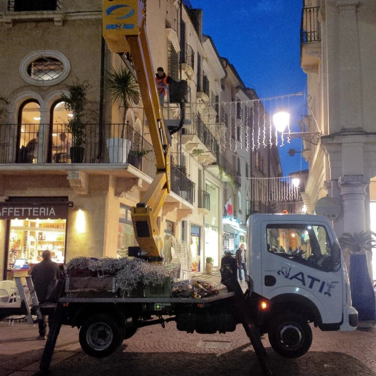 Workers hanging strings of Christmas lights on Piazza dei Signori - Vicenza, Italy - rossiwrites.com