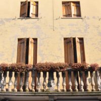 A peeling facade with a balcony and window shutters in Monselice, Colli Euganei, Italy