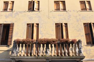 A peeling facade with a balcony and window shutters in Monselice, Colli Euganei, Italy