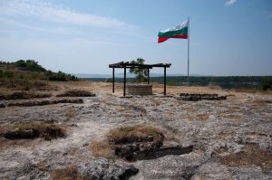 The Bulgarian flag, a well and the remnants of the medieval Metropolitan church, Ovech Fortress, Provadia, Bulgaria - www.rossiwrites.com