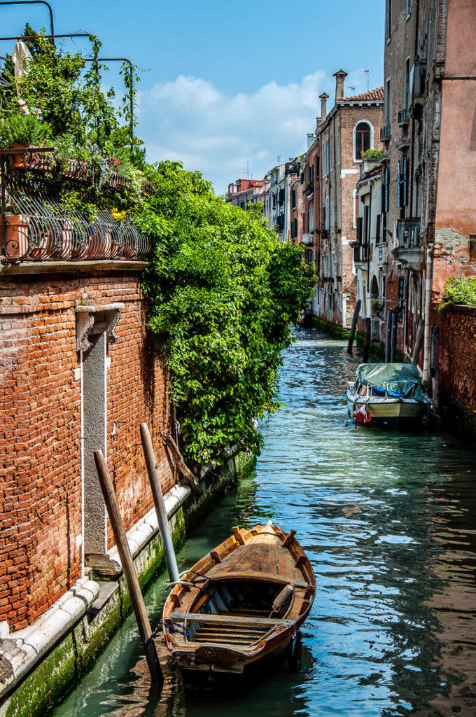 Venetian boat moored in a canal by a brick wall - Venice, Italy - rossiwrites.com