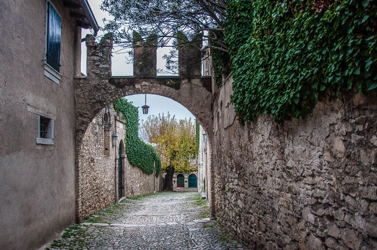 A cobbled street with the thick defensive wall of Villa Guarienti di Brenzone - Punta di San Vigilio - Lake Garda, Italy - rossiwrites.com