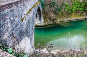 The Roman bridge over the river Sentino with the Abbey of San Vittore delle Chiuse - Marche, Italy - rossiwrites.com