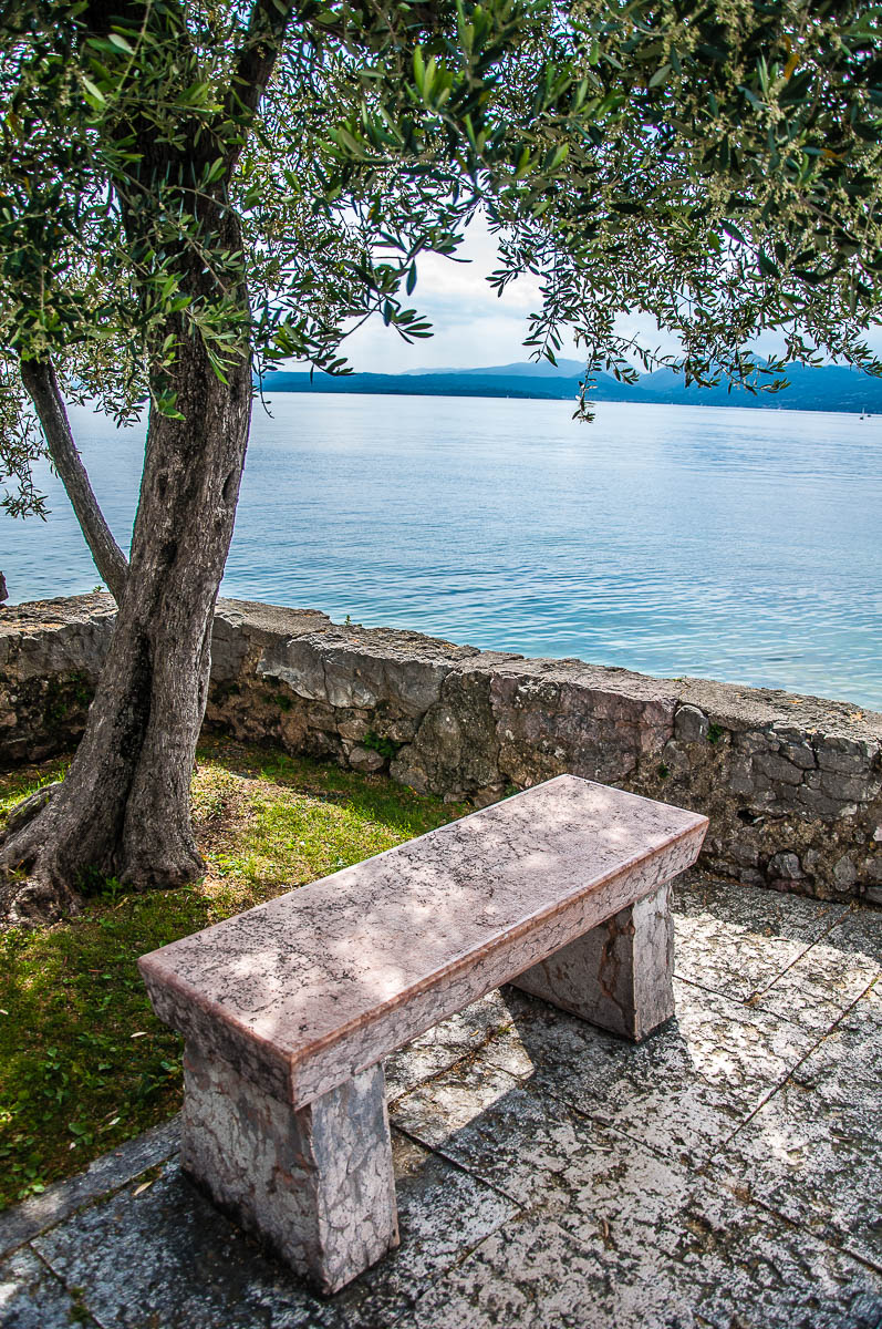 Bench on the edge of the historic harbour and overlooking Lake Garda - Torri del Benaco, Italy - rossiwrites.com