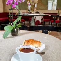 A Pedrocchi coffee served with a pastry on a table decorated with an orchid- Caffe Pedrocchi - Padua, Italy - rossiwrites.com