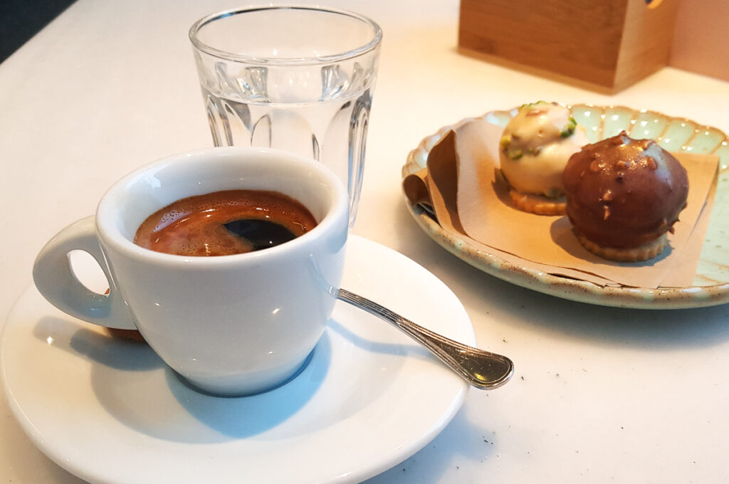 Espresso served with a glass of water and two chocolate sweets - Vicenza, Italy - rossiwrites.com