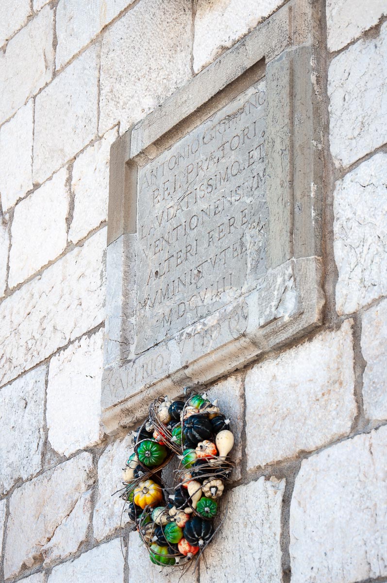 Pumpkin wreath attached to the facade of the Palazzo Comunale - Venzone, Italy - rossiwrites.com