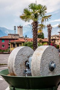 Olive grinding stones with the Scaliger Castle in the backdrop - Malcesine, Italy - rossiwrites.com