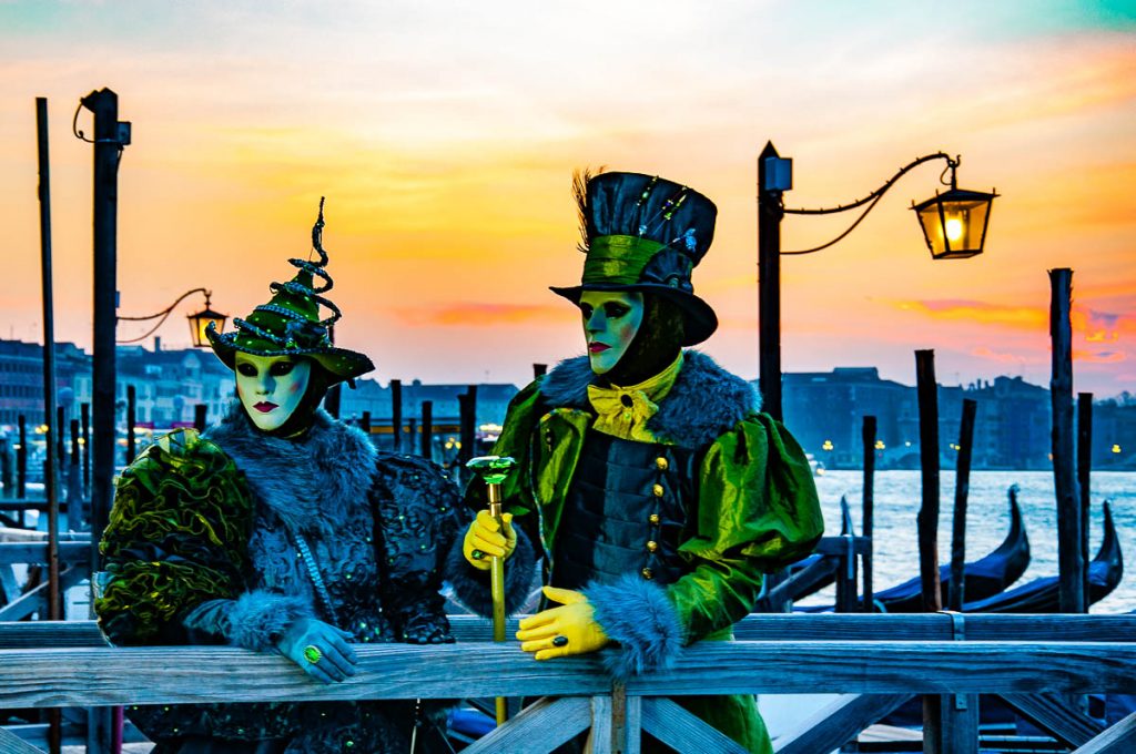 A male and female beautiful Venetian masks under an orange dawn - Venice Carnival, Italy - rossiwrites.com