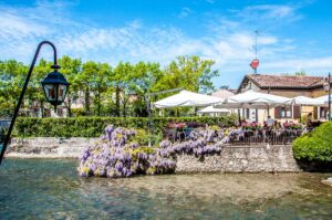 Local restaurant on the water surrounded by blooming wisterias - Borghetto sul Mincio, Italy - rossiwrites.com