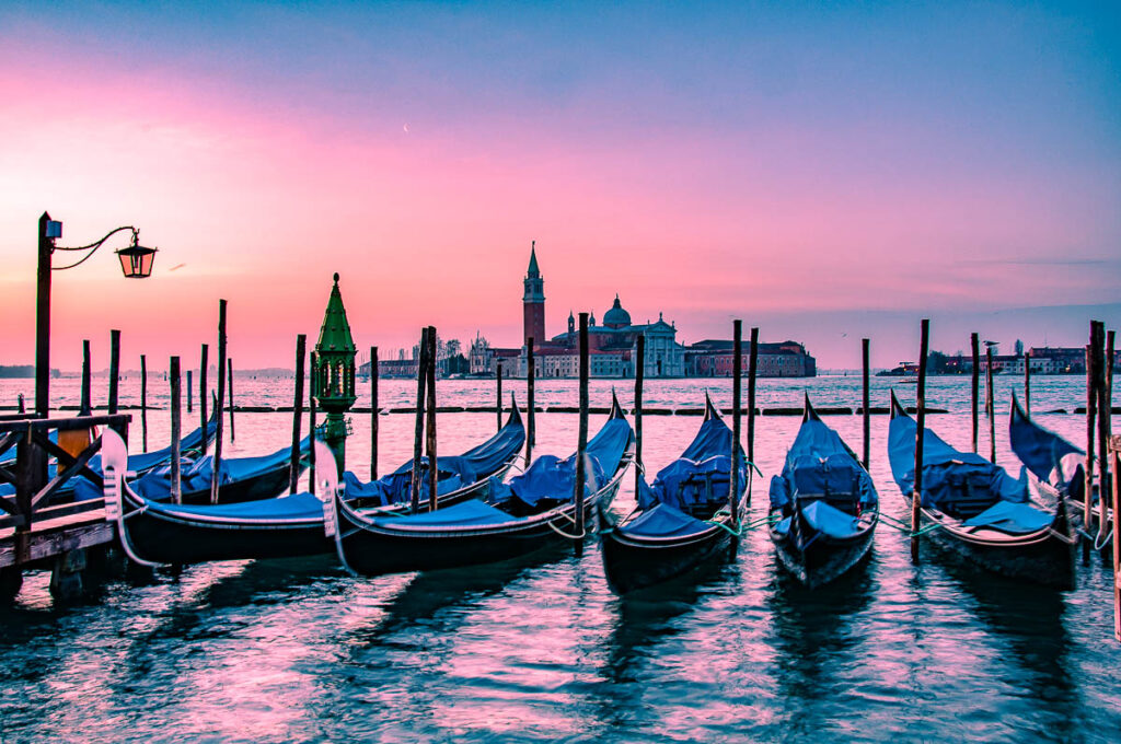Venetian gondolas and the island of San Giorgio Maggiore under an orange dawn - Venice, Italy - rossiwrites.com