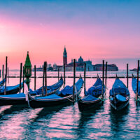 Venetian gondolas and the island of San Giorgio Maggiore under an orange dawn - Venice, Italy - rossiwrites.com