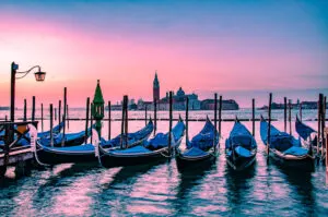 Venetian gondolas and the island of San Giorgio Maggiore under an orange dawn - Venice, Italy - rossiwrites.com