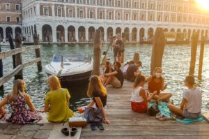 Tourists picnicking on a quay near Rialto Bridge - Venice, Italy - rossiwrites.com