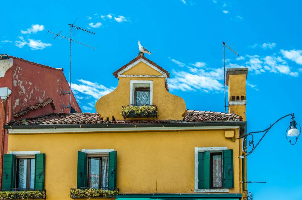 Bright yellow house under a blue sky on the island of Burano in Italy - rossiwrites.com