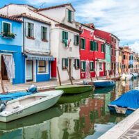 Colourful houses flanking a canal with boats on the island of Burano in Italy - rossiwrites.com