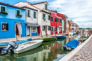 Colourful houses flanking a canal with boats on the island of Burano in Italy - rossiwrites.com