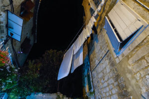 A clothesline with white laundry in the old town at night - Trogir, Croatia - rossiwrites.com