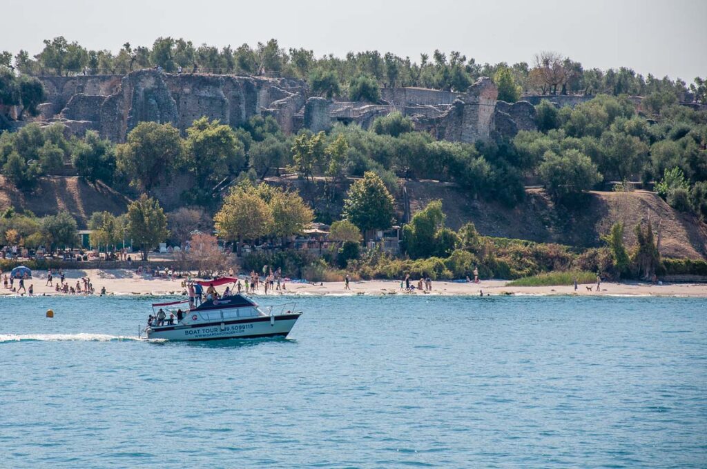 Boat in front of Jamaica Beach and Grotte di Catullo - Sirmione, Lake Garda, Italy - rossiwrites.com