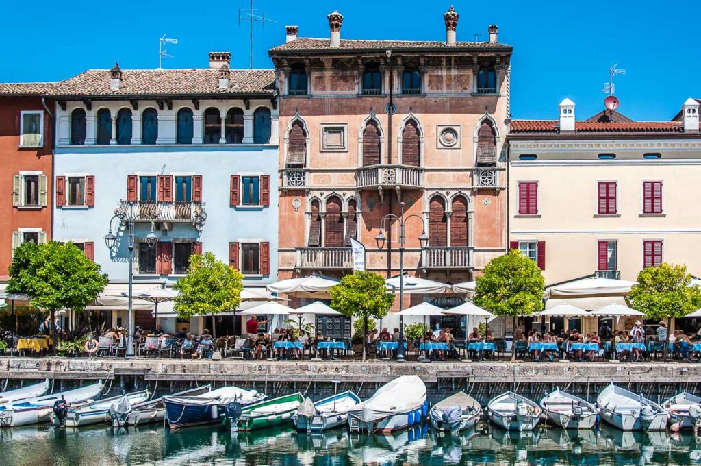 The tables of the local restaurants line up the historic harbour - Desenzano del Garda, Italy - rossiwrites.com