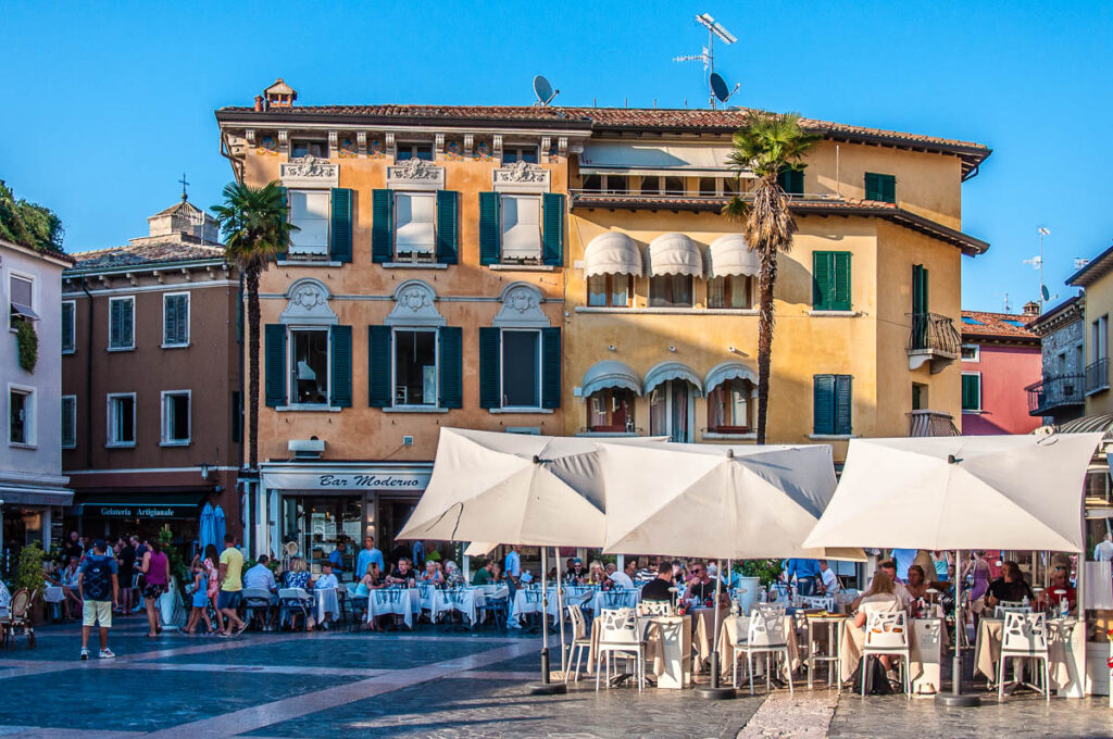 The tables of the local restaurants lined up on a central square in the town of Sirmione - Lake Garda, Italy - rossiwrites.com