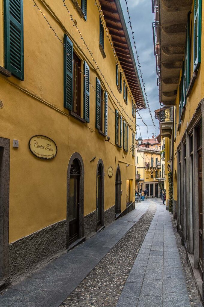 Narrow street flanked by yellow buildings in the town of Bellagio - Lake Como, Italy - rossiwrites.com
