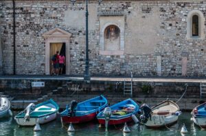 Boats with the centuries-old Church of San Nicolo in the town of Lazise - Lake Garda, Italy - rossiwrites.com