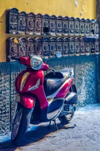 Red moped in front of rows of post boxes - Naples, Italy - rossiwrites.com