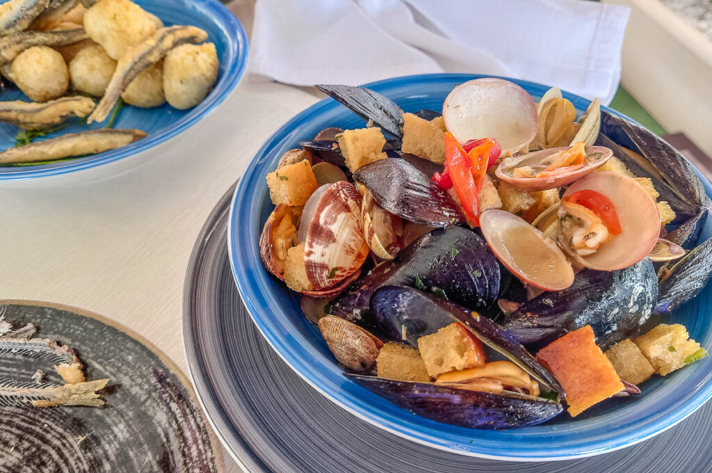 Sauté of mussels and clams with a portion of fried anchovies with zeppoline dough balls as served in a small restaurant in Molo di Bahia - Naples, Italy - rossiwrites.com