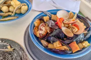 Sauté of mussels and clams with a portion of fried anchovies with zeppoline dough balls as served in a small restaurant in Molo di Bahia - Naples, Italy - rossiwrites.com