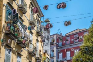 Street in Rione Sanita with rows of hats hanging above it - Naples, Italy - rossiwrites.com
