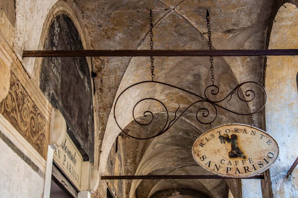 The sign of a local restaurant hanging in a portico - Treviso, Italy - rossiwrites.com