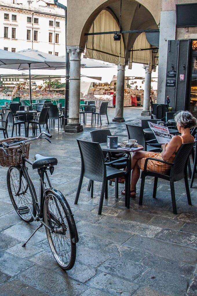 A lady reading a newspaper at a coffee shop on Piazza delle Erbe - Padua, Italy - rossiwrites.com